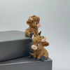 A small, brown Highland cow statue with horns sitting on a dark gray surface.