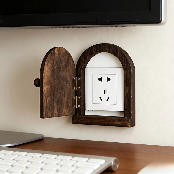 A wooden decorative outlet cover is mounted on a wall, featuring an arched opening to reveal a white electrical outlet.