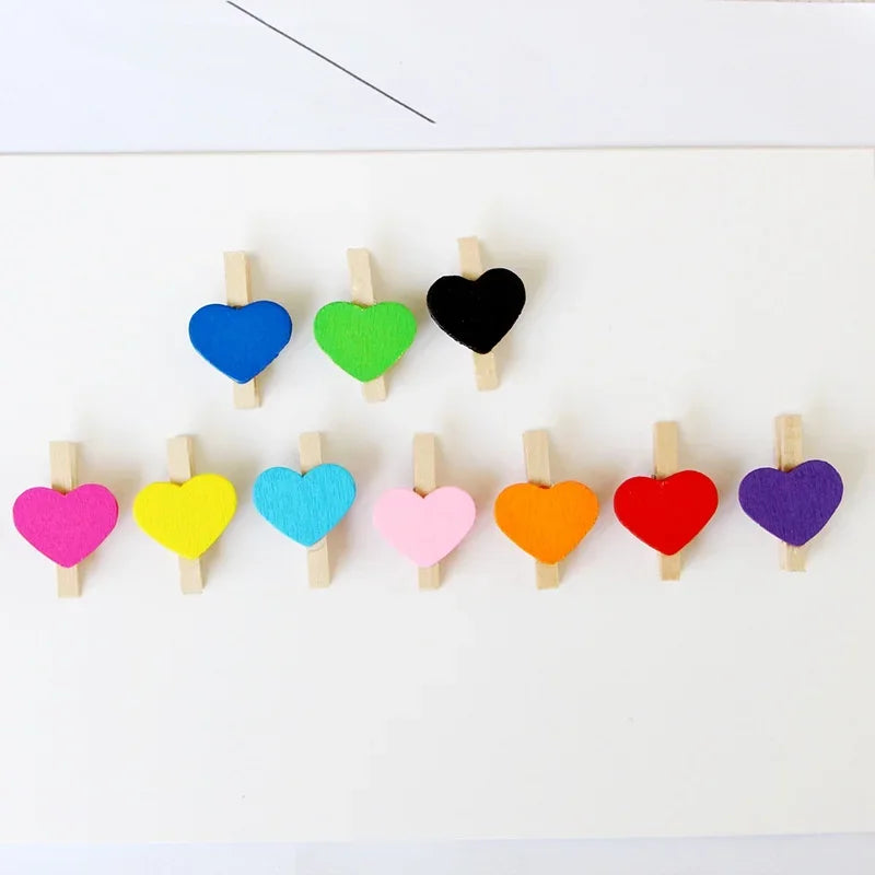 A collection of mini wooden heart clips in various colors including blue, green, black, pink, yellow, orange, and red.