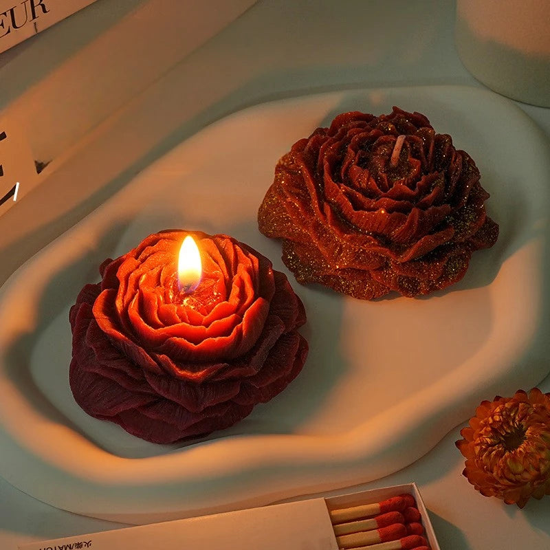Nahaufnahme einer handgemachten Rosen-Peony-Duft-Sojawachs-Kerze, die auf einer weißen Platte brennt.