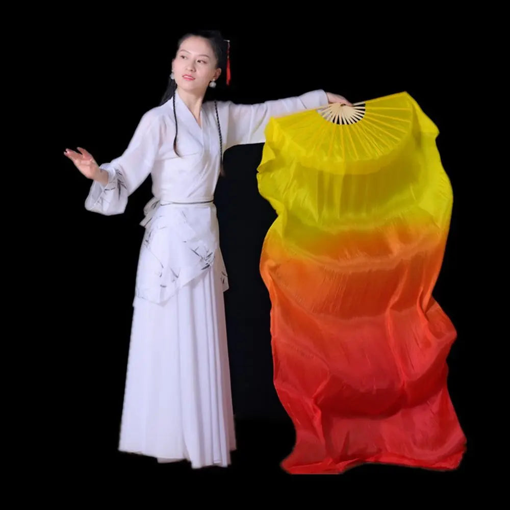 A woman in a white traditional outfit holds a large yellow and orange gradient silk ribbon dance fan.