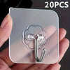 A clear adhesive wall hook with a silver hook is shown being held in a hand against a light background.