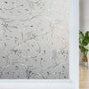Close-up of frosted window privacy film featuring delicate silver floral and vine patterns.