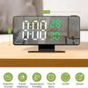 A black LED digital projection alarm clock displaying time, temperature, and humidity on a wooden surface.