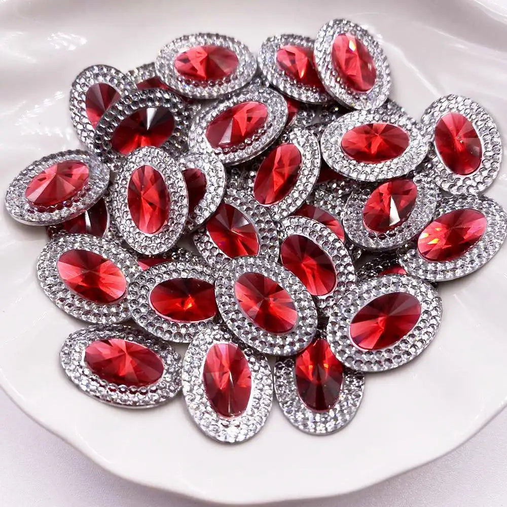 A pile of red gemstone flatback rhinestones with silver settings on a white surface.