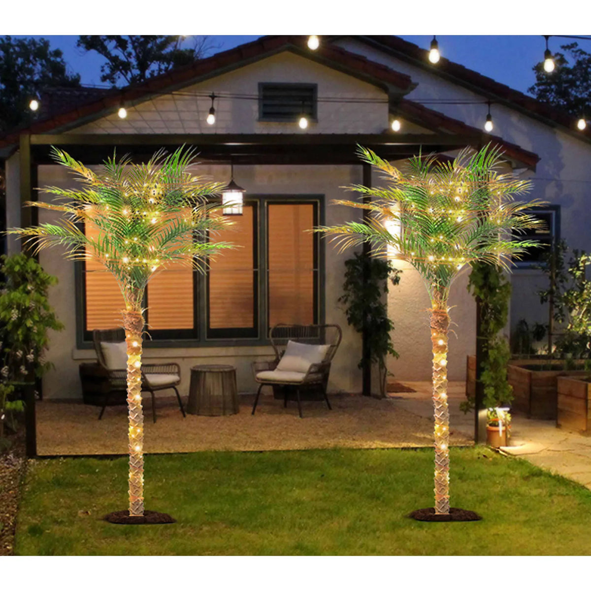 Artificial golden palm trees with lights decorating a backyard patio area at dusk.