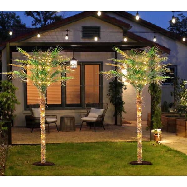 Artificial golden palm trees with lights decorating a backyard patio area at dusk.