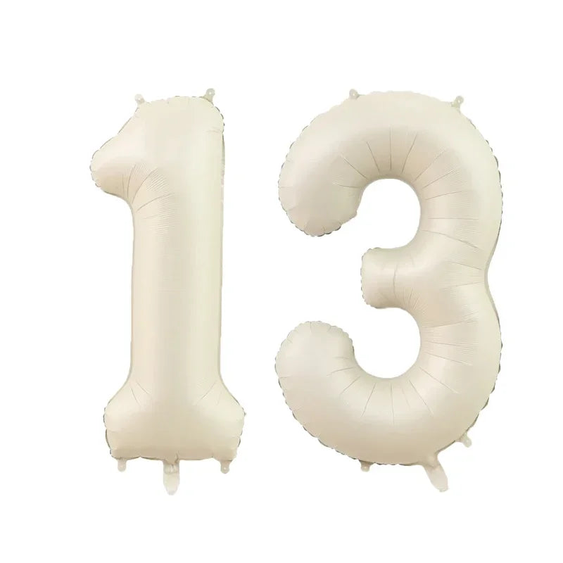 A set of gold silver black helium foil number balloons forming the number 13.