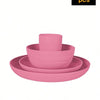 A stack of four pink reusable plastic tableware items including a bowl and plates.