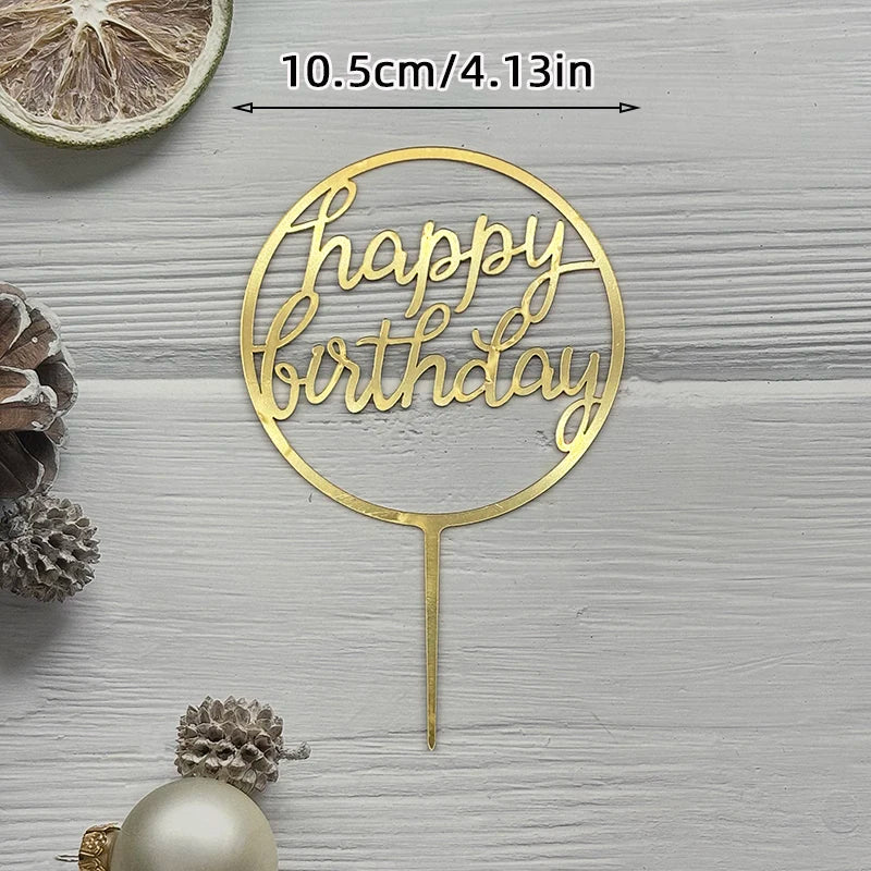 A gold acrylic cake topper with the words Happy Birthday on a thin stick, set against a light wooden background.