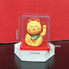 A yellow solar-powered waving lucky cat figurine displayed in a clear box on a white stand.