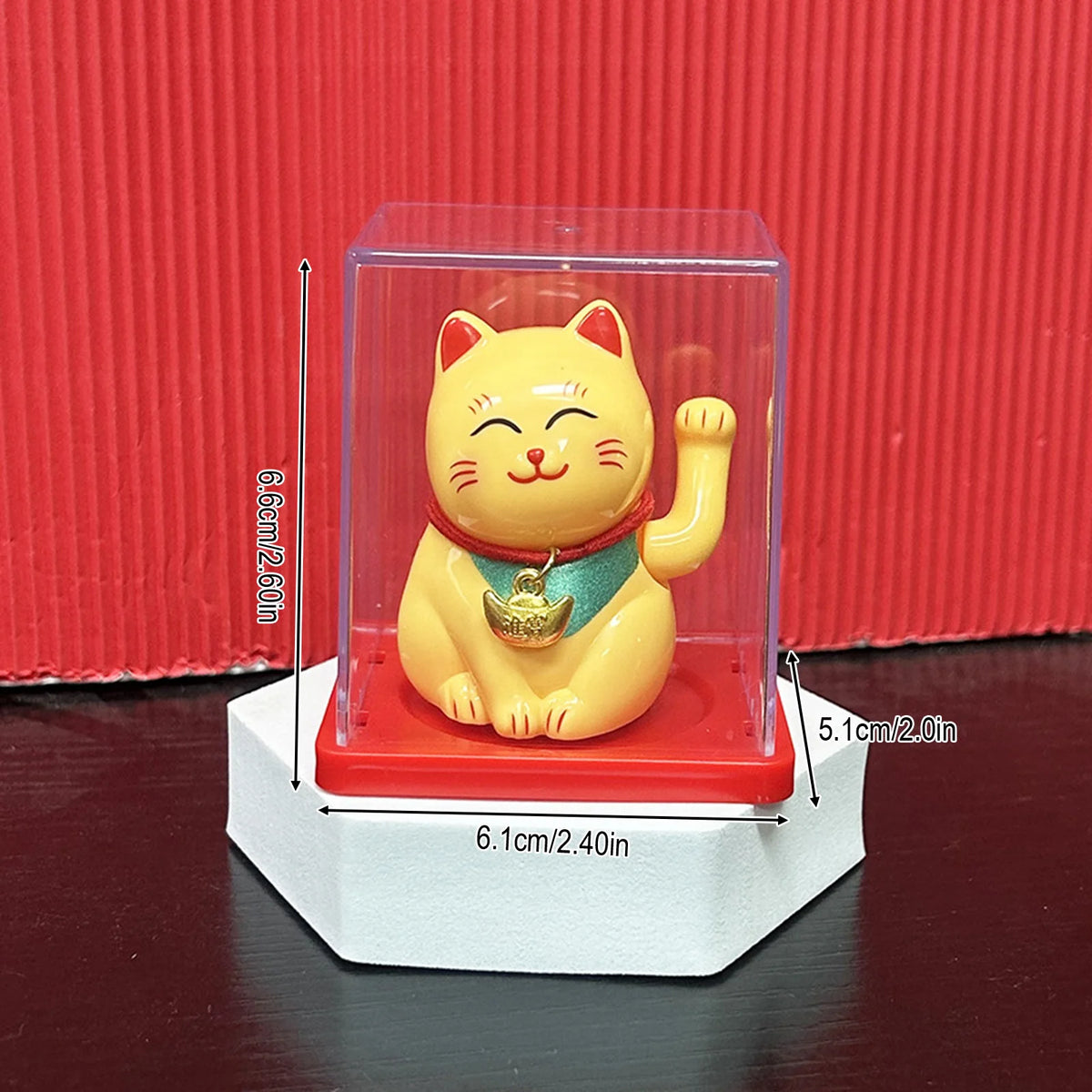 A yellow solar-powered waving lucky cat figurine displayed in a clear box on a white stand.