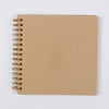 A spiral-bound kraft paper scrapbook notebook with gold-toned metal rings.