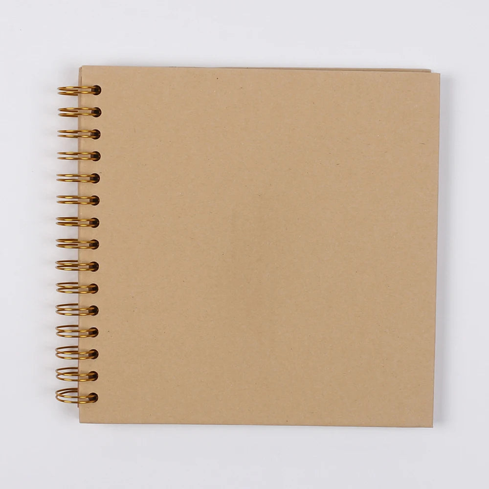 A spiral-bound kraft paper scrapbook notebook with gold-toned metal rings.