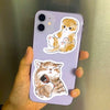 A purple smartphone features a sticker design of a cute, fluffy orange cat sitting down.