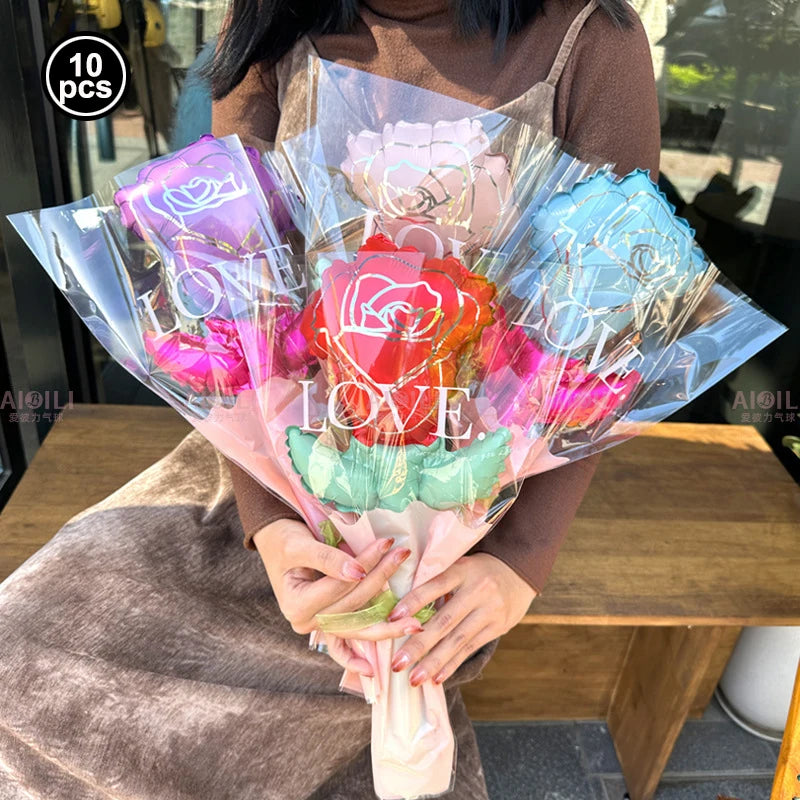A bouquet of red and pink heart-shaped balloons with foil finish held by a person.