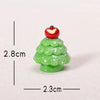 A small green resin Christmas tree charm with a red apple topper, shown against a white background.