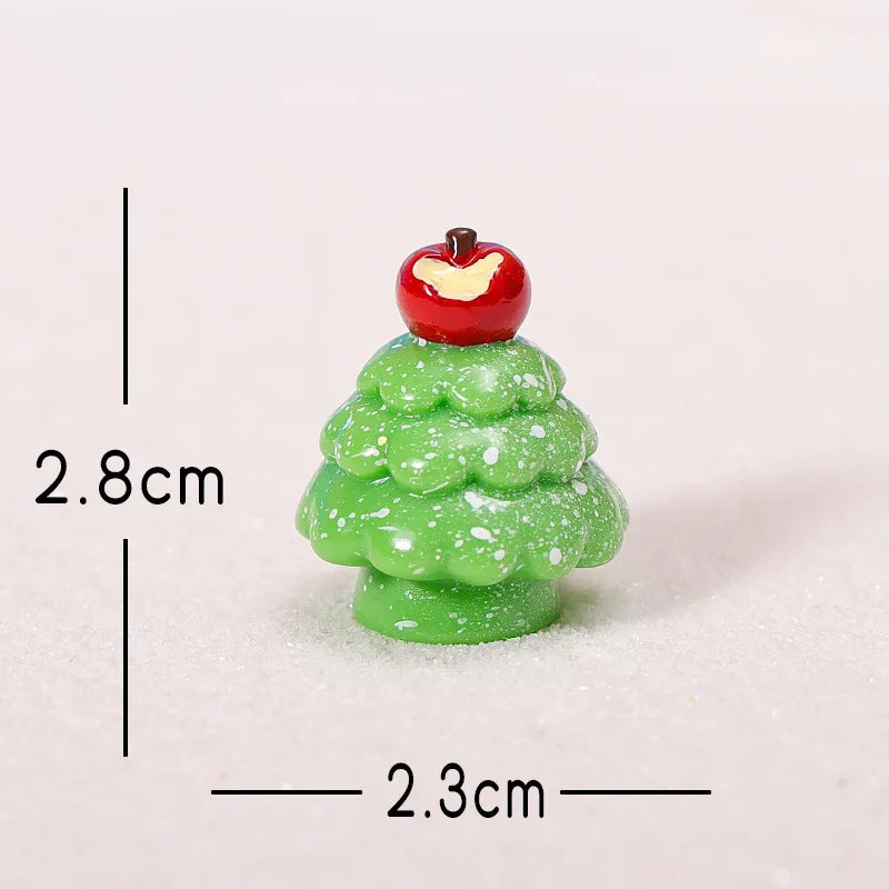 A small green resin Christmas tree charm with a red apple topper, shown against a white background.