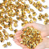 A hand holds a pile of gold-colored decorative acrylic ice rocks or gems.