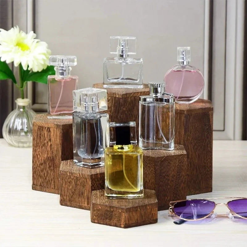 A collection of glass perfume bottles displayed on a wooden hexagonal rack with a white flower in the background.