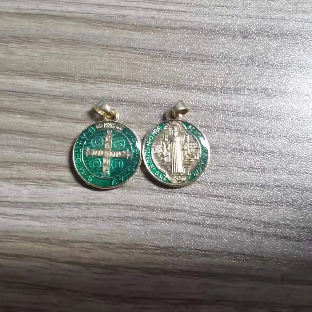 A pair of silver-toned religious pendants featuring a cross design and a depiction of Jesus Christ.