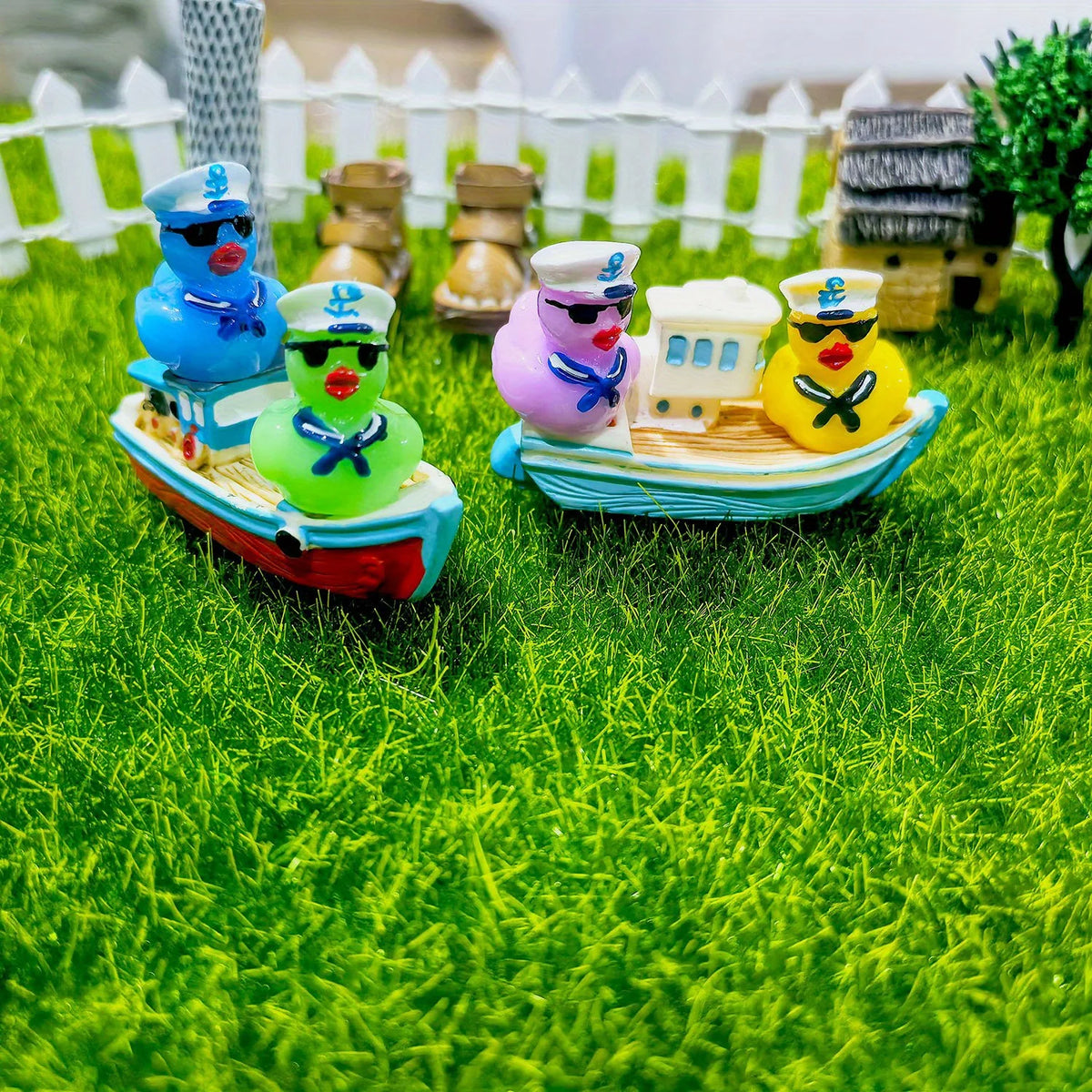 A set of three mini resin cruise ducks with sunglasses in blue, green, and yellow on a wooden boat.