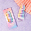 A package of long thin spiral birthday candles in pastel colors is shown against a purple background.