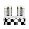 A white cake decorated with black and white checkered frosting and topped with numerous candles and star toppers.