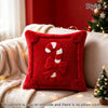 A red velvet pillow cover featuring a white candy cane bow design on one side, displayed on a sofa with holiday lights.
