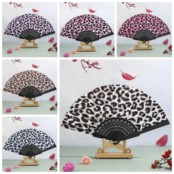 A collection of leopard print folding hand fans shown in various angles and colors on a light green surface.