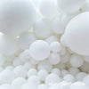 A close-up view of a large pile of matte white latex balloons.