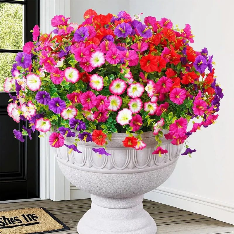 A vibrant bouquet of artificial silk cloth flowers in shades of pink, red, and purple displayed in a white urn.