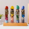 Four glass bottles filled with colored crystals representing zodiac signs standing on a wooden base
