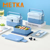 A light blue bento lunch box set with compartments and utensils is displayed on a white surface.