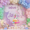 A pink and yellow unicorn cake decoration set featuring flowers, stars, and balls displayed on a white stand.