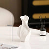 White ceramic vase with an abstract grass motif displayed on a white surface.
