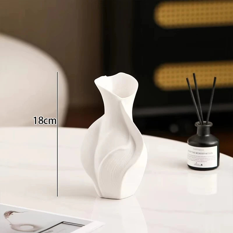 White ceramic vase with an abstract grass motif displayed on a white surface.