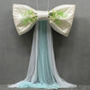 A white satin bow with green floral accents and a long, sheer light blue tulle drape for event decor.