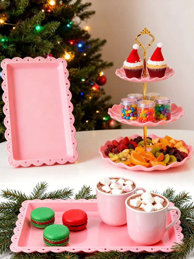 A three-tier pink dessert rack holds various colorful candies and desserts on a white surface.