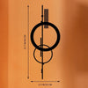Minimalistische geometrische Wandskulptur mit konzentrischen Kreisen und vertikalen Linien an einer orangefarbenen Wand.