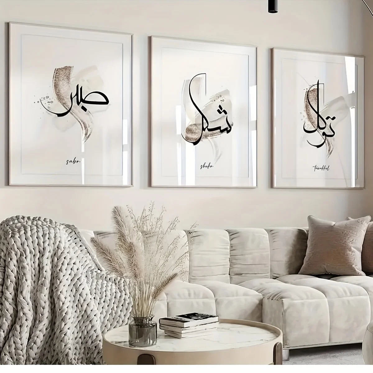 A gallery wall featuring three framed Islamic calligraphy pieces on a light-colored wall above a beige sofa.