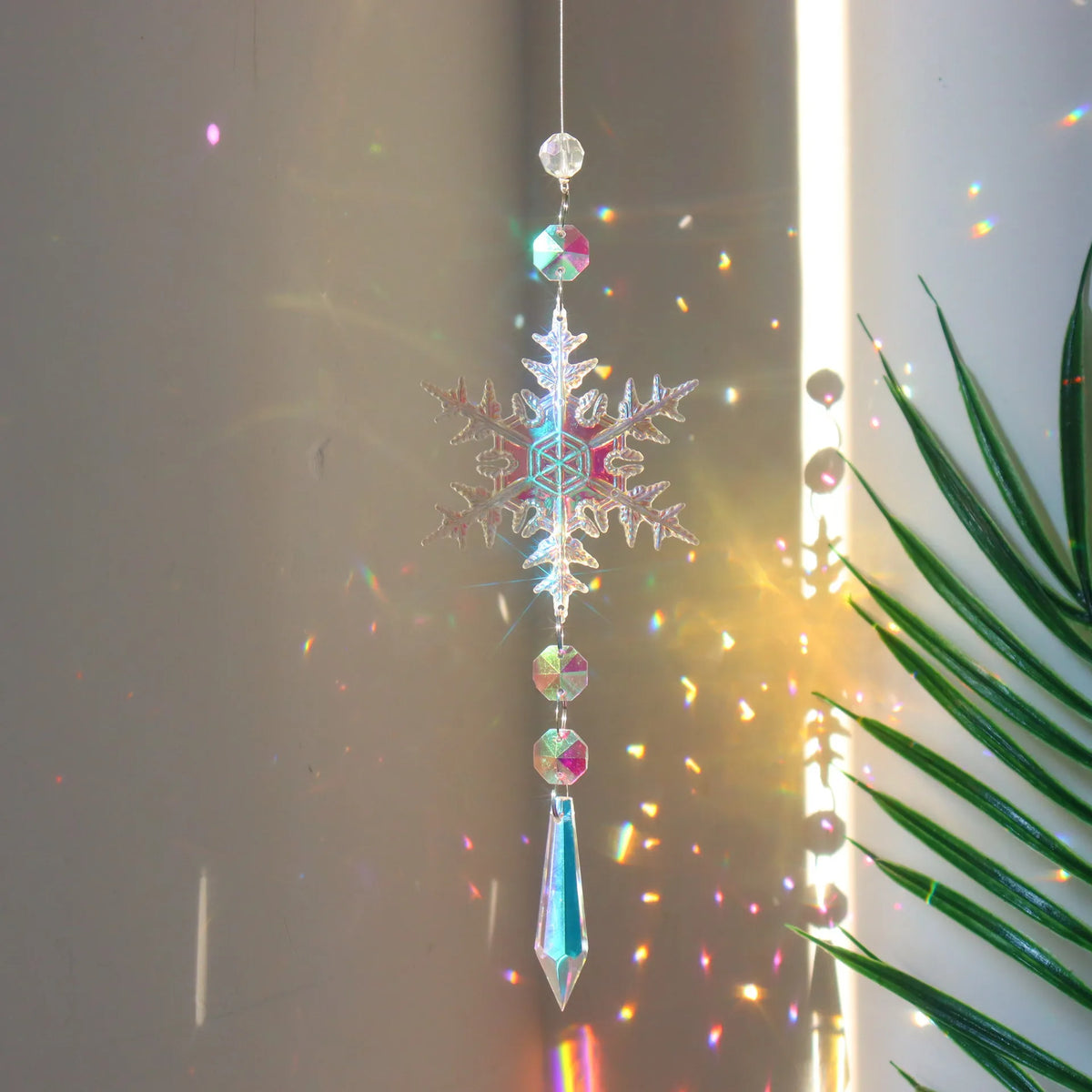 A hanging crystal rainbow wind chime decor featuring a snowflake-shaped pendant and various colored crystals.
