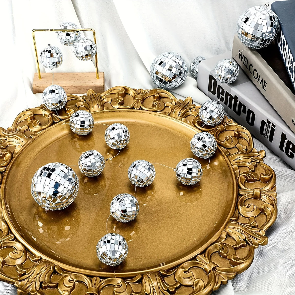 A set of ten silver disco ball ornaments displayed on a gold platter with ornate detailing.