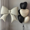 A cluster of heart-shaped foil balloons in black and white are displayed against a light gray wall.