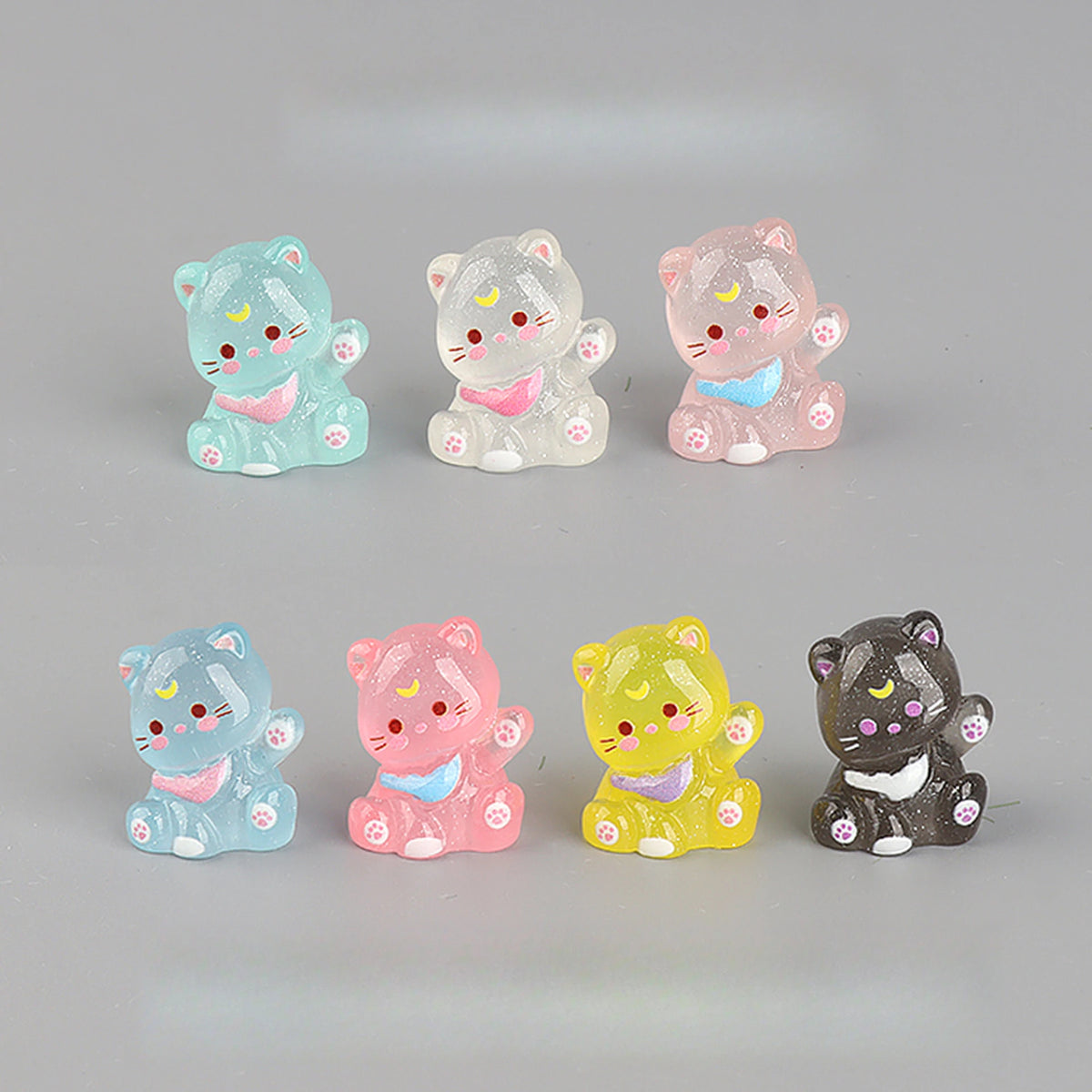 A collection of six pink and white cat-shaped resin keychains in various pastel colors and shades.