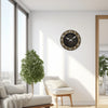 Horloge murale ronde en bois avec calligraphie islamique, accrochée à un mur blanc près d'une grande fenêtre et d'un arbre en