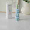 A tall, stacked candle holder with pastel blue and green candles and a pink wand, displayed next to its packaging.