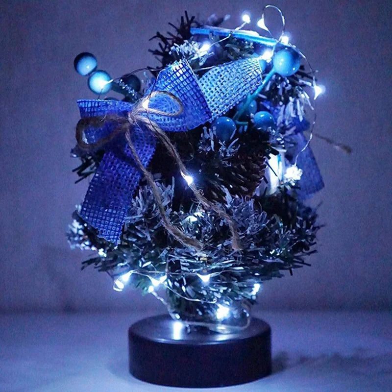 A festive decoration featuring blue fairy lights wrapped in a purple ribbon and adorned with dark greenery.