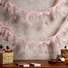 A delicate pink tulle bow garland strung across a light gray background for party decoration.