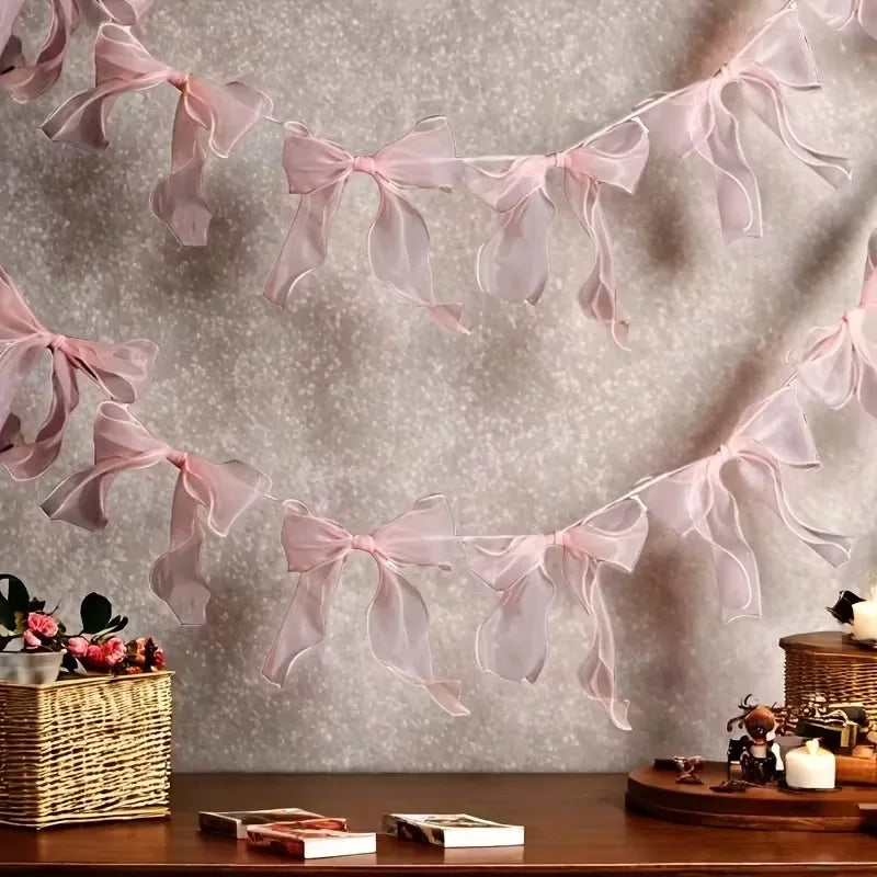 A delicate pink tulle bow garland strung across a light gray background for party decoration.
